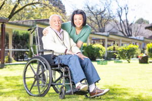 caregiver helping an elderly man on wheelchair