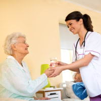 caregiver brings water to senior woman