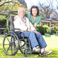 caregiver helping an elderly man on wheelchair